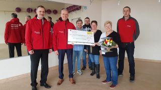 v.l.n.r.: Marek Pazda und Steffen Glatz von der Sparkasse Uckermark, vom Verein SV Topfit Prenzlau Finanzfrau Barbara Thielemann, Übunglseiterin Martina Rösler und ihr Mann Hartmut Rösler, Übungsleiter Badminton und Trampolin, Vorstand Thomas Wendlandt und (mit Blumen) Vereinsvorsitzende Marianne Gerling, Bild: Antenne Brandenburg/Sabine Kramm