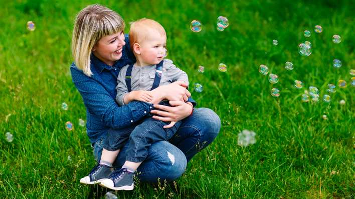 Frau mit Kind auf dem Arm gucken Seifenblasen hinterher, Foto: Colourbox Frau mit Kind auf dem Arm gucken Seifenblasen hinterher, Foto: Colourbox