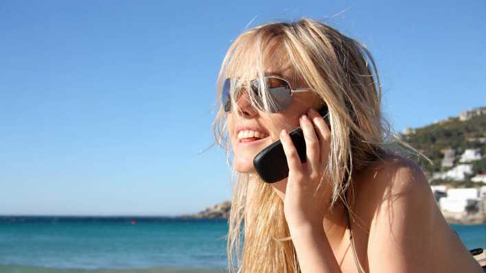 Junge Frau telefoniert am Strand, Bild: imago-images Junge Frau telefoniert am Strand, Bild: imago-images
