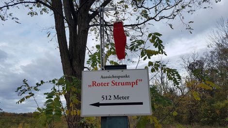 Das Hinweisschild zum Aussichtspunkt erinnert an die Siedlung der Böhmischen Glasmacher, die hier lebten und rote Strümpfe trugen, Bild: Antenne Brandenburg/Iris Wußmann