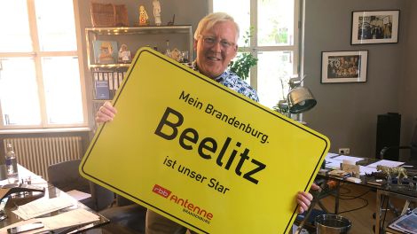 Beelitz Bürgermeister Bernhard Knuth mit dem Antenne Ortsschild, Bild: Antenne Brandenburg / Johanna Siegemund