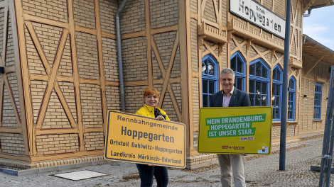 Hoppegartens Bürgermeister Sven Siebert erhält ein neues Ortsschild von Antenne-Reporterin Eva Kirchner-Rätsch