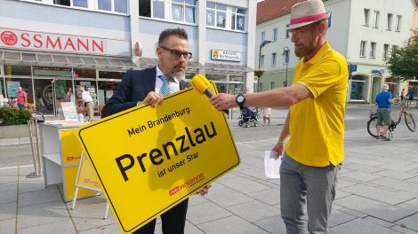 Prenzlaus Bürgermeister Hendrik Sommer nimmt von Antenne-Moderator Alex Dieck ein Ortsschild entgegen, Bild: Antenne Brandenburg/Alexander Heisig