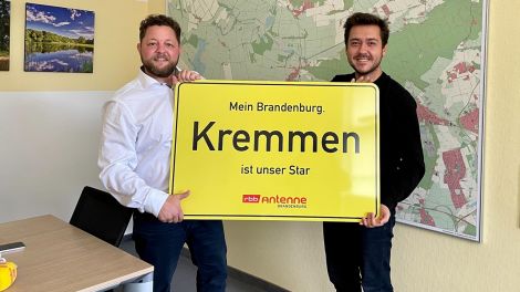 Antenne-Reporter Christofer Hameister übergibt Bürgermeister Sebastian Busse das Schild "Kremmen ist unser Star", Foto: Antenne Brandenburg