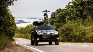 Auto mit einer Dachbox und einen Fahrrad auf dem Dach, Foto: Colourbox