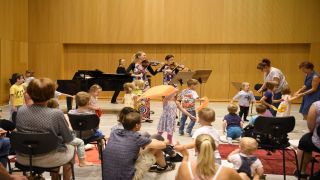 Kinder erleben ein Orchester und tanzen mit Tüchern