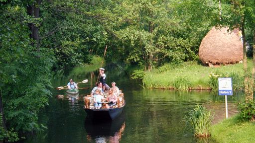 Ein besetzter Spreewaldkahn passiert einen Bereich mit typischen Heuschobern aus dem Spreewald (Quelle: TMB-Fotoarchiv/TVb (c))