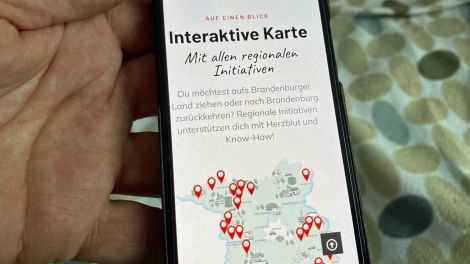 Auf einem Handydisplay ist die Homepage der Ankommen-Initiative zu sehen